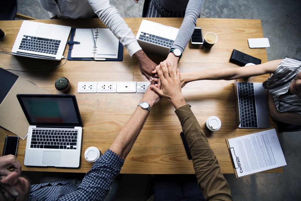A group of people sitting at a desk with a laptop on a table